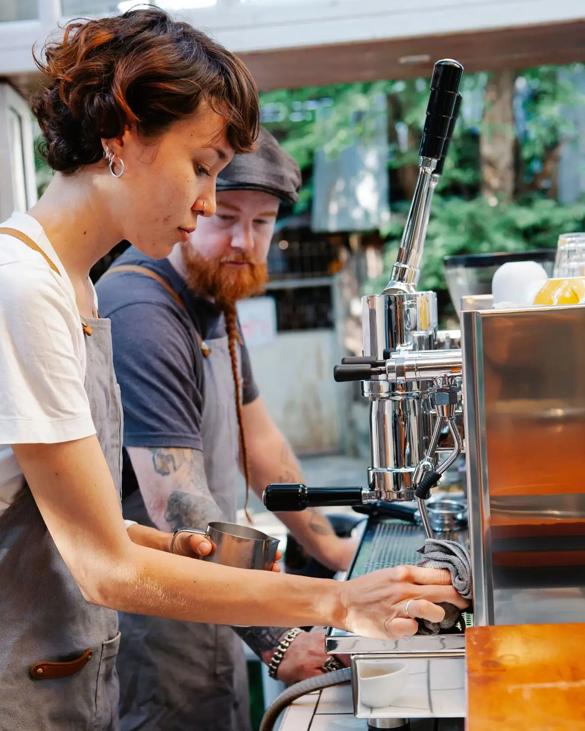 En erfaren barista handleder en ny kollega som gör en espresso.